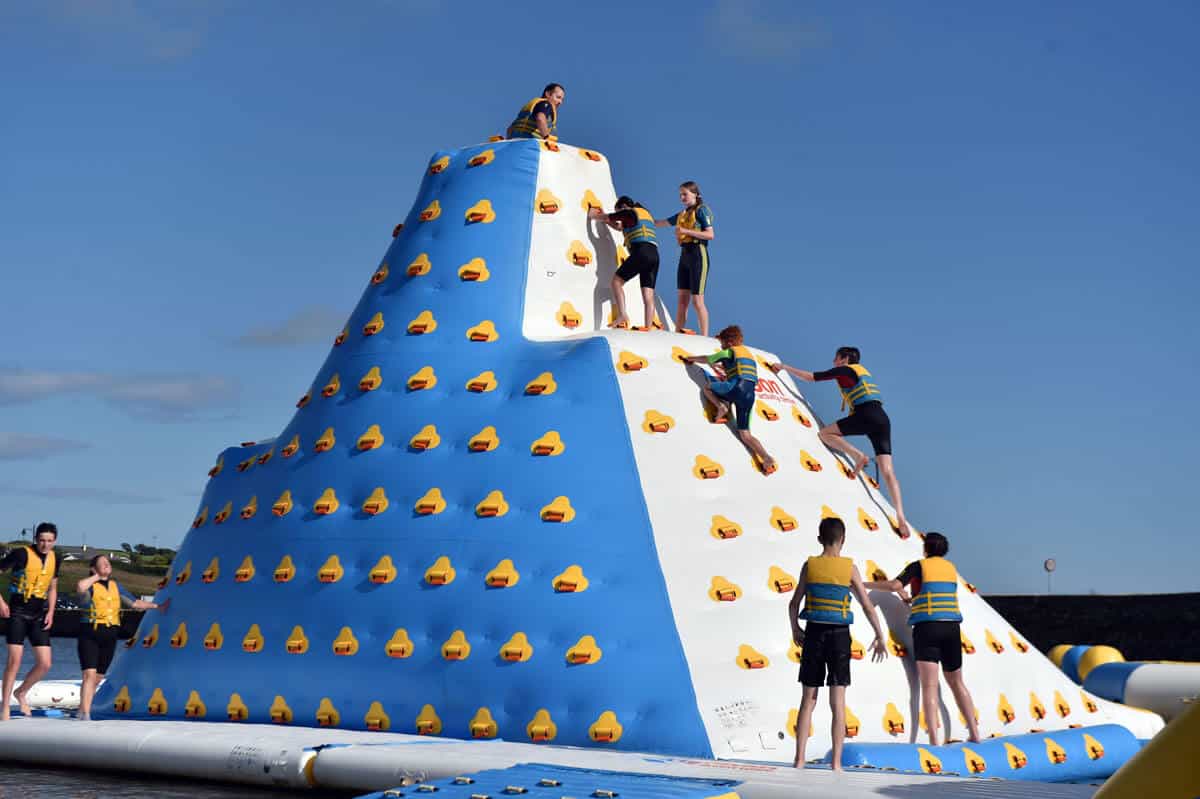 Group of people climbing the 9m tall "iceberg" obstacle in the Rosscarbery's aqua park