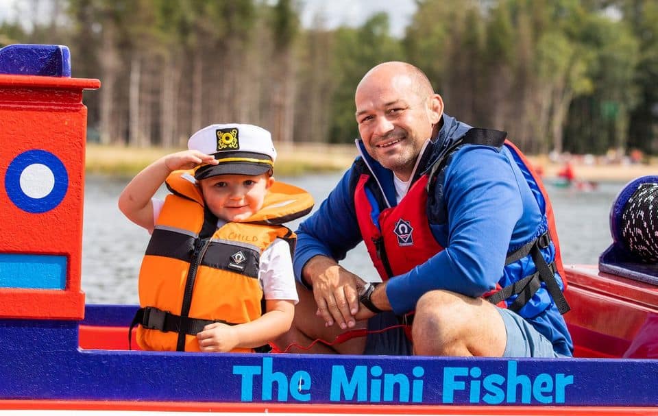 Young child and adult enjoying a calm ride in a colourful Mini Captain watercraft on the lagoon at The Lagoon Activity Centre.