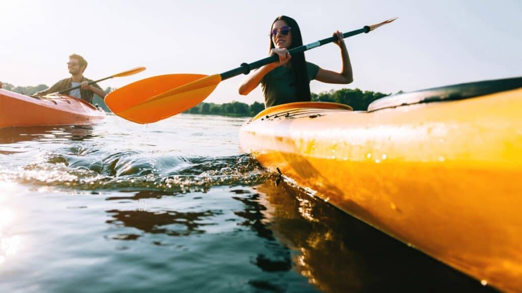 Couple kayaking together on calm water in bright summer sunlight in West Cork
